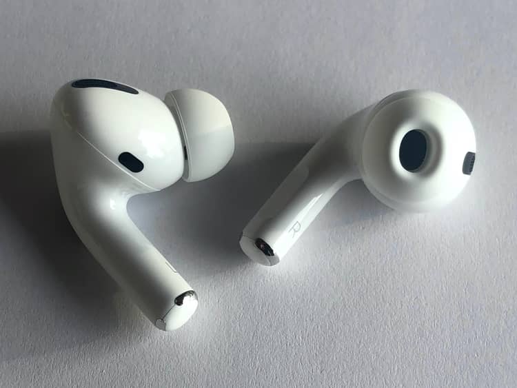 First-generation AirPods Pro pair on a white table, silicone tips and inner stem marks visible